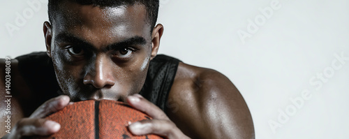 Obraz na płótnie Close-up of a determined male basketball player covered in sweat holding a basketball with both hands while staring intensely forward against a neutral studio background w salonie