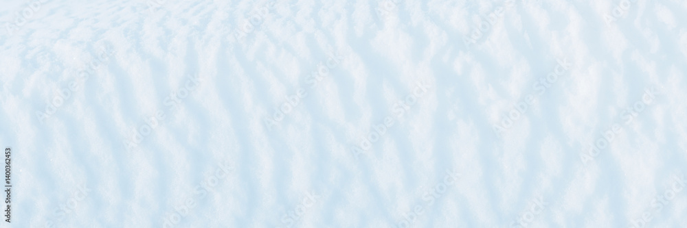 Wide panoramic winter background with snowy ground. Natural snow texture. Wind sculpted patterns on snow surface.