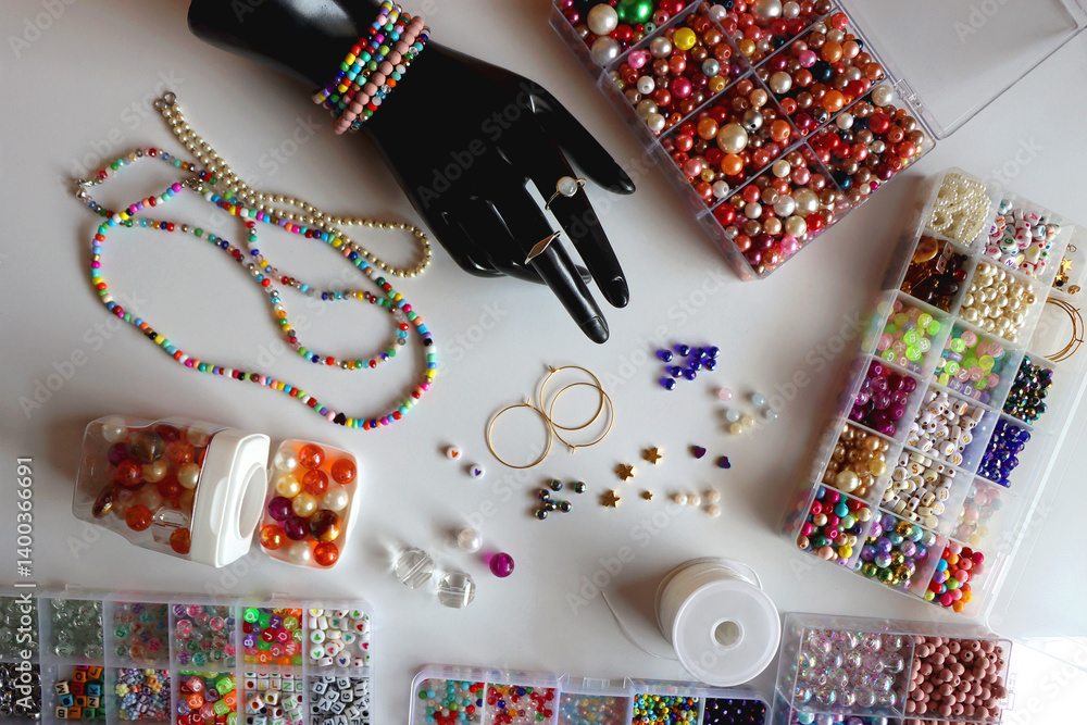 Hand figurine, colorful friendship bracelets, necklaces, various beads and DIY supplies on the table. Making jewelry at home. Flat lay.