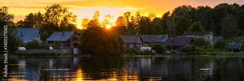Evening summer landscape with wooden houses on the shore of the lake. Panoramic view of a small provincial Russian town. Beautiful sunset over Lake Valdayskoye. Valday, Novgorod region, Russia.