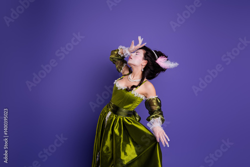 Fototapeta Elegant young woman posing in green historical dress with violet background