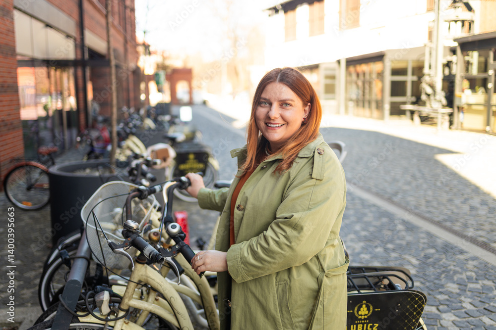A young woman wearing a green jacket smiles as she stands next to a row of bicycles, ready to explore the city. The scene is set in an urban environment with a modern vibe, highlighting the city's
