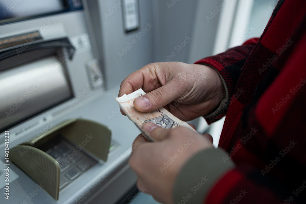 A person withdrawing cash in Polish zloty from an ATM. The image shows the convenience of accessing local currency through automated teller machines in Poland