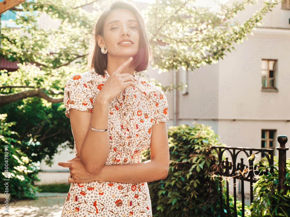Naklejka premium Portrait of young beautiful smiling woman in trendy summer sundress. Sexy carefree woman posing on the street background at sunset. Positive model outdoors