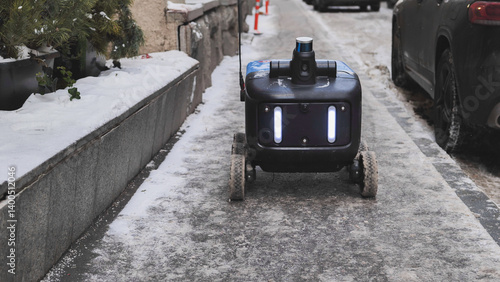 Photography Autonomous delivery robot moving on a snowy sidewalk in Moscow.