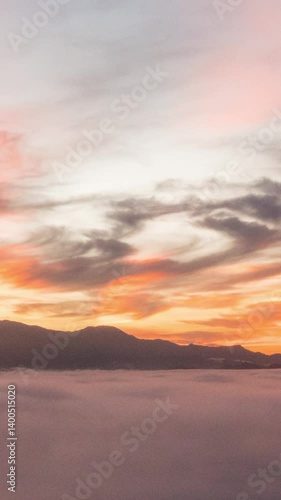 A peaceful 4K timelapse loop capturing dense stratus clouds slowly drifting through lush mountain ridges. The soft white clouds roll like mist across the valleys ,Vertical timelapse video.