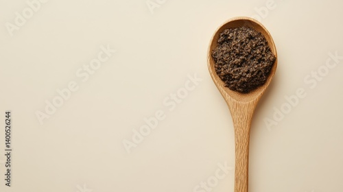 A single wooden spoon containing olive tapenade, isolated on light background with top view and balanced layout