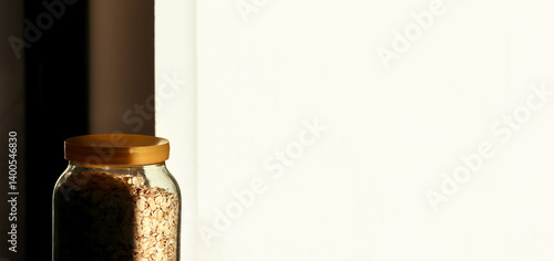 Obraz na płótnie A minimalistic scene featuring a jar of oatmeal against a clean white background, with subtle shadows adding depth to the composition. Banner for design with copy space w salonie