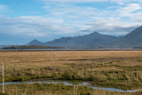 Icelandic landscape: mountains, grassland, and cloudy sky.