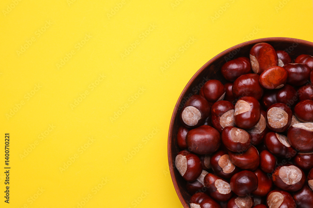 Obraz premium Lots of chestnuts in a bowl on yellow background. Top view