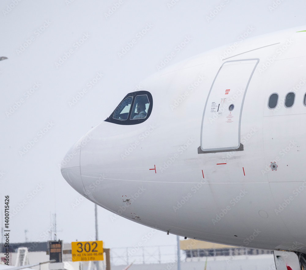 Pilot sitting in cockpit of modern white airplane on runway Pilot sitting in cockpit of modern white airplane on runway