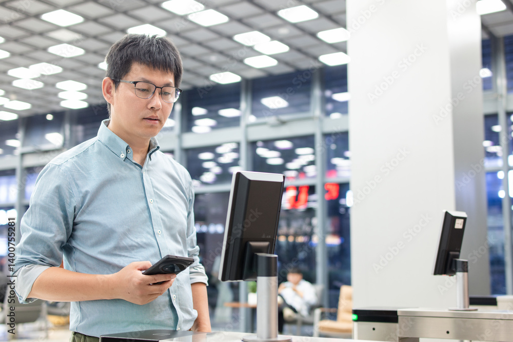 Fototapeta premium An Asian business man passes through the access control turnstile of the office building by facial recognition