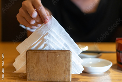 Person Taking Napkin from Wooden Holder at Restaurant