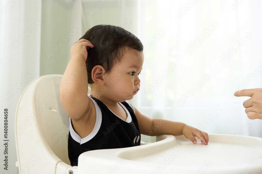 The baby is sitting in a high chair, and the person is pointing at something. The baby appears to be looking up while the person points. The baby is sitting in a high chair, and the person is pointing at something. The baby appears to be looking up while the person points.