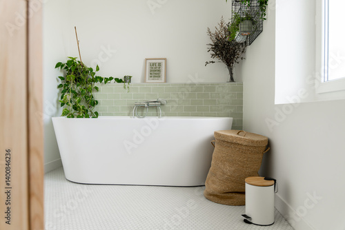 Schilderij op canvas Salle de bain rénovée avec baignoire îlot blanche, carrelage en zellige vert clair, plantes vertes, panier à linge en osier et meuble en bois