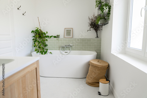 Carta da parati Salle de bain rénovée avec baignoire îlot blanche, carrelage en zellige vert clair, plantes vertes, panier à linge en osier et meuble en bois