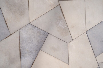 A geometric pattern of polygonal tiles in neutral tones, creating a modern and stylish design for outdoor or indoor flooring. Design of a sidewalk in a public park.