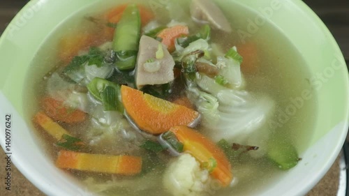 Vegetable soup with cauliflower, meatball, white cabbage, carrots, green peas on wooden background