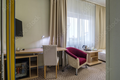 Modern hotel room with desk and armchairs