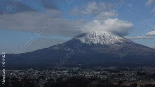 Timelapse of mount Fuji in Japan with snow at the top of mountain in blue and cloudy sky.