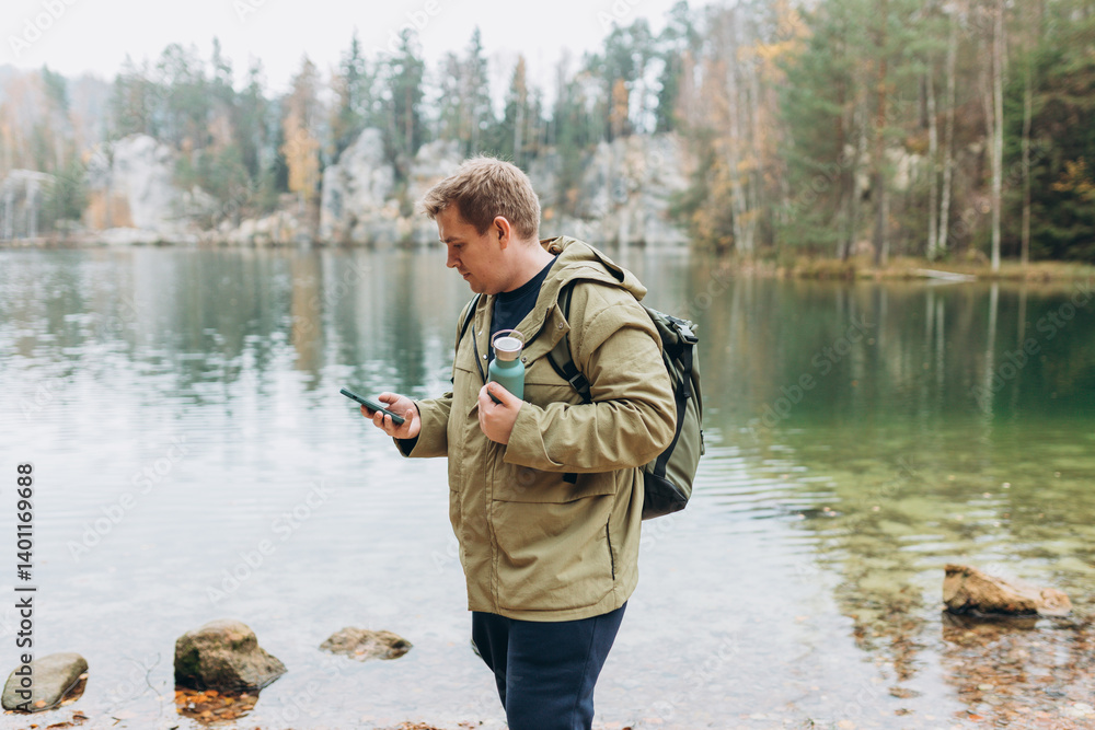 Travel backpacker standing with phone near the majestic lake. Travel, adventure. Concept of an active lifestyle. High quality photo