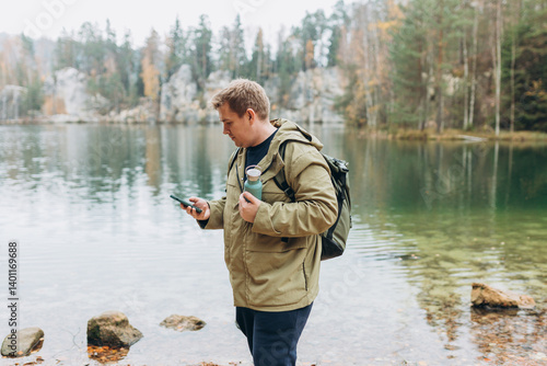 Obraz na płótnie Travel backpacker standing with phone near the majestic lake. Travel, adventure. Concept of an active lifestyle. High quality photo w salonie