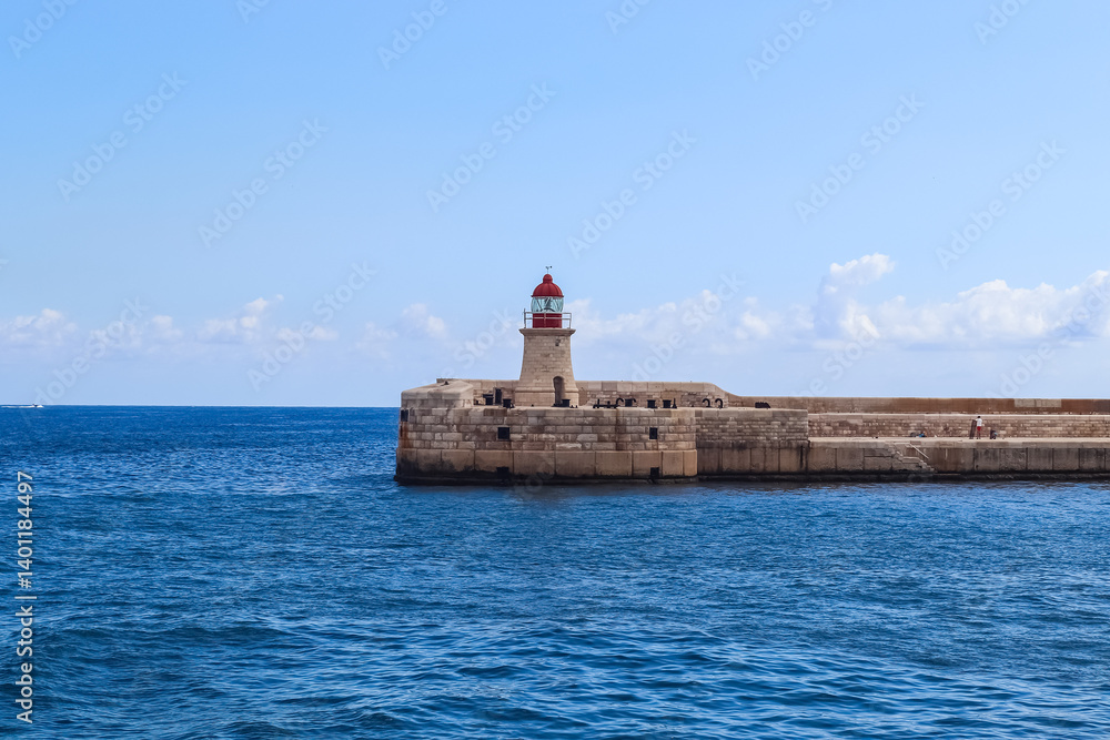 Valletta, Malta 28 September 2024: Ricasoli Lighthouse rising from the blue Mediterranean sea in Malta, Grand Harbor Valletta, Malta 28 September 2024: Ricasoli Lighthouse rising from the blue Mediterranean sea in Malta, Grand Harbor