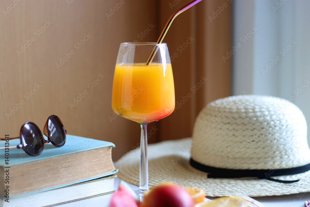 Glass of cocktail, straw hat, sunglasses, books, fresh fruit, chocolate and accessories. Summer essentials on the table. Selective focus.
