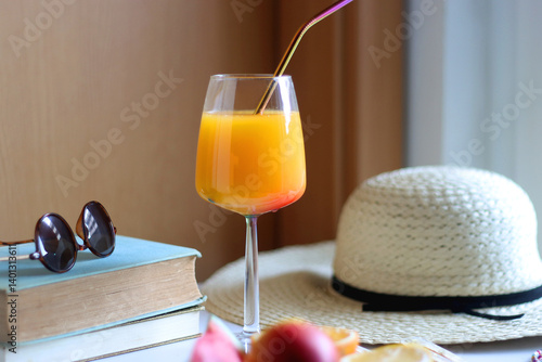 Obraz na płótnie Glass of cocktail, straw hat, sunglasses, books, fresh fruit, chocolate and accessories. Summer essentials on the table. Selective focus. w salonie