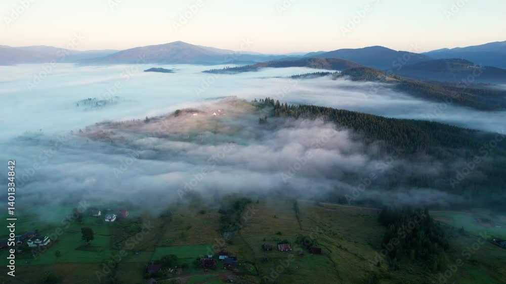 Aerial view of lush, green valley with scattered houses bathed in early morning sunlight. Mist rolls through forested hills, creating ethereal atmosphere against backdrop of distant mountains. Aerial view of lush, green valley with scattered houses bathed in early morning sunlight. Mist rolls through forested hills, creating ethereal atmosphere against backdrop of distant mountains.