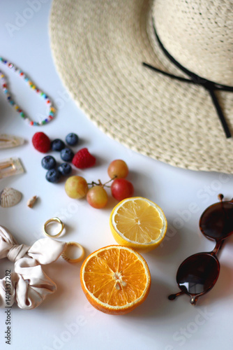 Straw hat, sunglasses, seasonal fruit, seashells and colorful accessories on white backgrounds. Cute summer essentials. Selective focus.