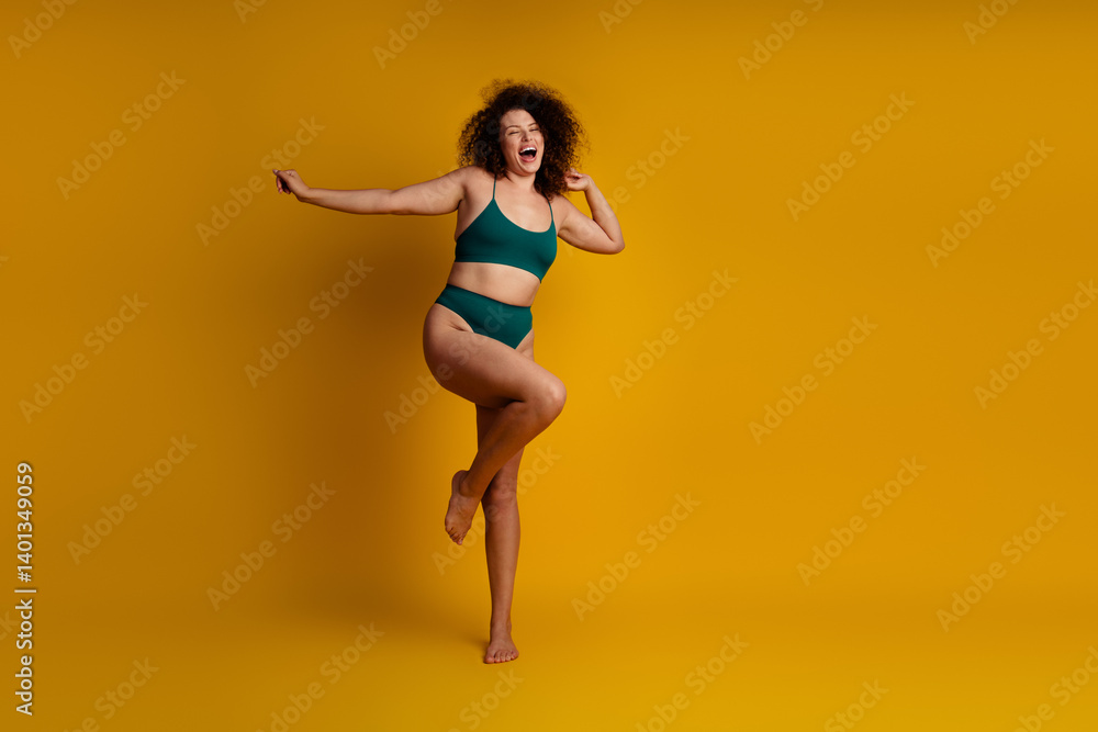 Confident young woman with curly hair showing self acceptance and positive energy against a vibrant yellow background Confident young woman with curly hair showing self acceptance and positive energy against a vibrant yellow background