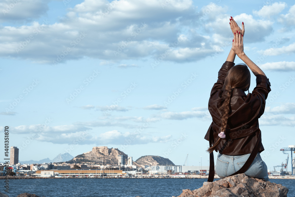Woman in leather jacket relaxing by the sea with scenic harbor landscape and dramatic sky Woman in leather jacket relaxing by the sea with scenic harbor landscape and dramatic sky