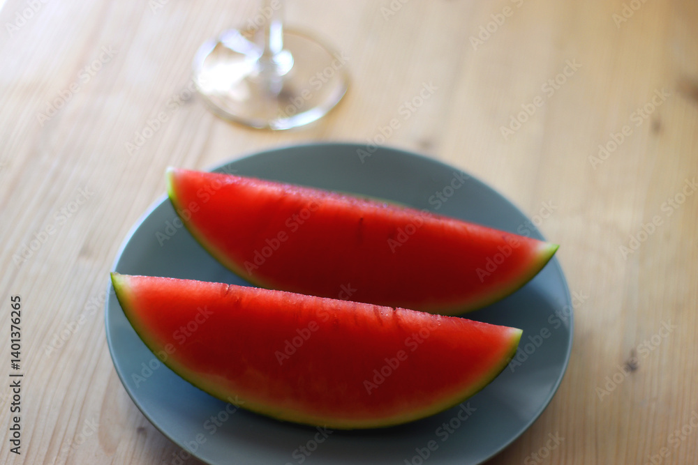 Plate with two watermelon slices and glass of orange juice on the table. Selective focus.