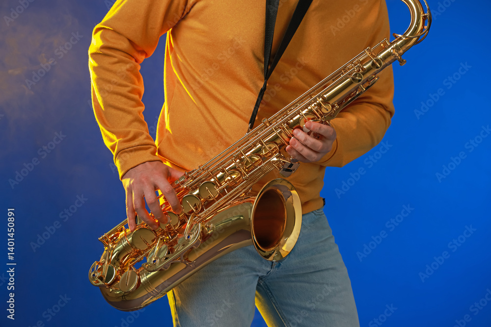 Naklejka premium Professional musician playing saxophone on blue background, closeup