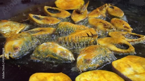 Hilsha fish is fried in a big pan along with shrimp and eggplant, Hilsha Fish and shrimp Simmering in mustard oil, traditional Bengali style fried hilsa and eggplant	