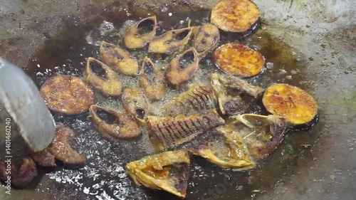 Hilsha fish is fried in a big pan along with shrimp and eggplant, Hilsha Fish and shrimp Simmering in mustard oil, traditional Bengali style fried hilsa and eggplant	
