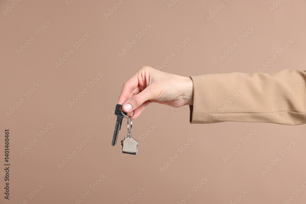 Real estate agent holding key with house shaped keychain on beige background, closeup Real estate agent holding key with house shaped keychain on beige background, closeup