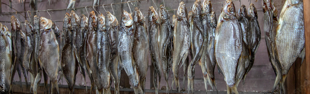 Close-up of dried fish hanging in rows on metal wire hooks outdoors Close-up of dried fish hanging in rows on metal wire hooks outdoors