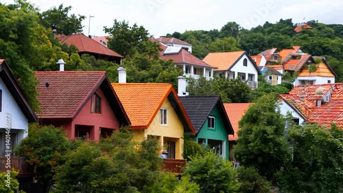 Wallpaper Mural Colorful houses lined along a hillside with lush greenery and distant rooftops under a clear sky Torontodigital.ca
