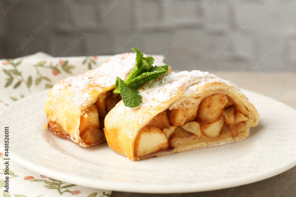 Pieces of tasty apple strudel with powdered sugar and mint on grey table, closeup Pieces of tasty apple strudel with powdered sugar and mint on grey table, closeup
