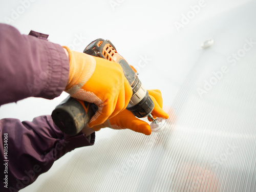 A man assembles a new greenhouse from polyethylene and polycarbonate