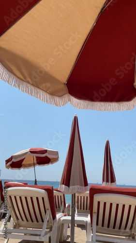 Im Wind wehende rot-weiße Sonnenschirme am Strand von Cannes, Frankreich 