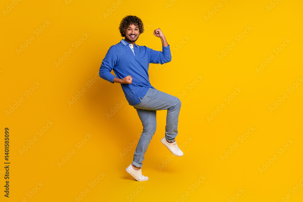 Fototapeta premium Young stylish male posing in a blue polo shirt with a vibrant yellow background conveying energy and modern style