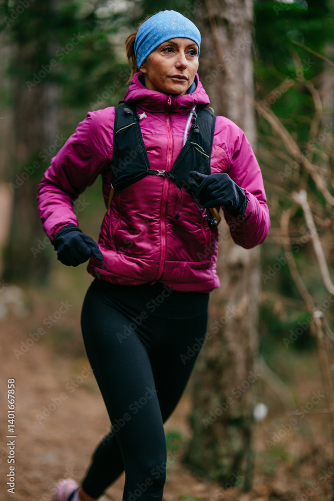Determined Female Athlete Running with Focus Through a Dense Pine Forest, Embracing Strength and Nature