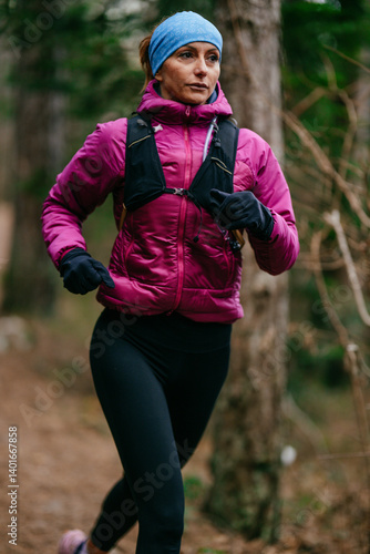 Obraz na płótnie Determined Female Athlete Running with Focus Through a Dense Pine Forest, Embracing Strength and Nature w salonie