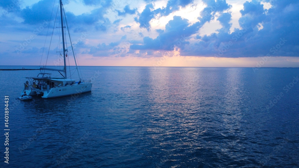 Fototapeta premium catamaran gently anchored on the calm, dark blue water at dusk
