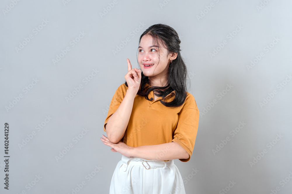 Young woman with a joyful facial expression, raising one finger as if having a sudden idea. Her bright smile and excited eyes capture the concept of a creative eureka moment. Young woman with a joyful facial expression, raising one finger as if having a sudden idea. Her bright smile and excited eyes capture the concept of a creative eureka moment.