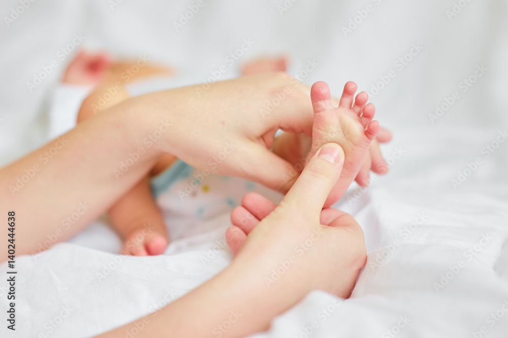 Parent Gently Massaging Infant's Tiny Foot on Soft White Bedding.. Parent Gently Massaging Infant's Tiny Foot on Soft White Bedding..