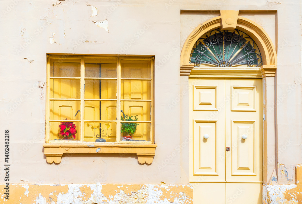 Facade of an old yellow residential building with peeling paint
